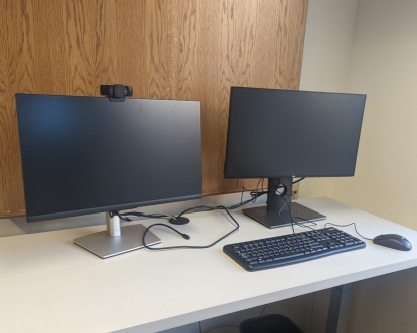 Example of 2 monitors with docking station, keyboard and mouse, and webcam that is available in each reservable office.